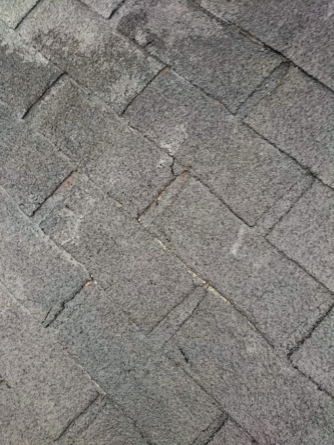 大阪府東大阪市、石粒が脱落し色あせたアスファルトシングルの屋根。