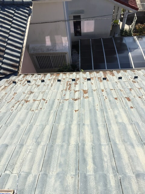 1階部分の屋根。セメント瓦の表面が剥がれ落ち、茶色い素地が広範囲に見えている状態