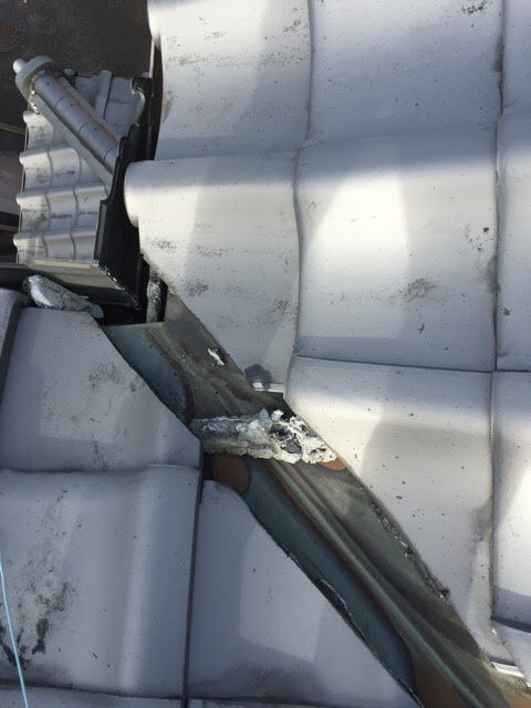 東大阪市の屋根雨漏り調査。谷樋（たにとい）の銅板が変色し、剥がれた漆喰の塊が詰まっている危険な状態。