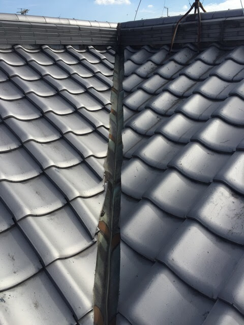 東大阪市の屋根雨漏り調査。谷樋（たにとい）の銅板が変色し、剥がれた漆喰の塊が詰まっている危険な状態。