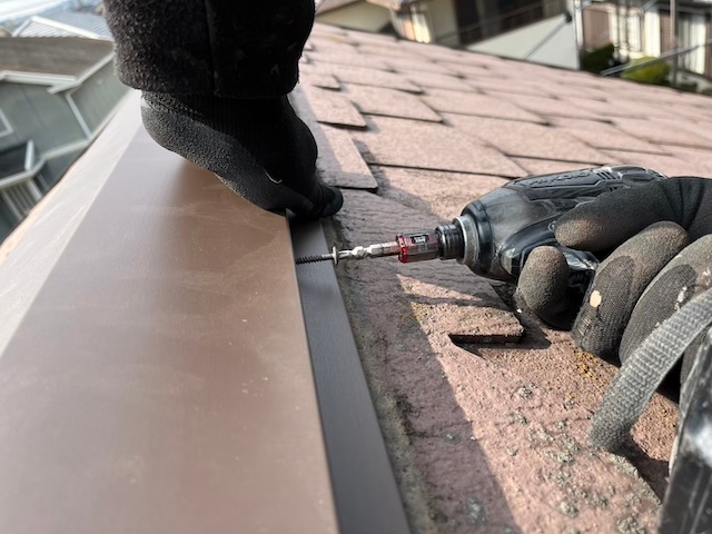 棟板金をインパクトドライバーで強固にビス止め固定する様子