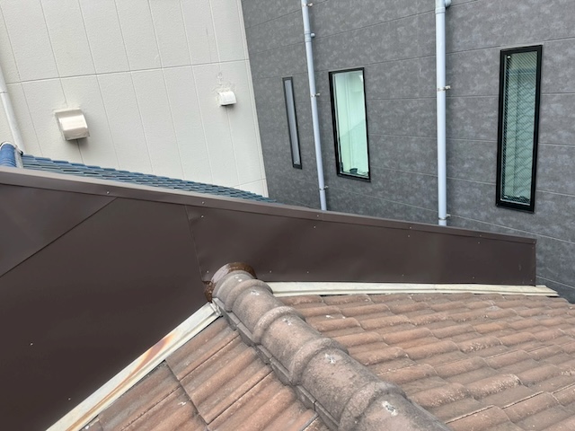 ガルバリウム鋼板で美しく仕上げられた柏原市の外壁。瓦屋根との接合部も処理され工事完了