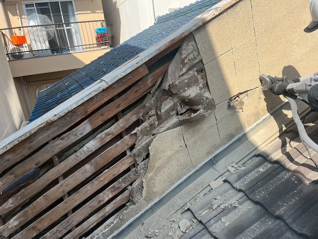 剥がれかけた危険なモルタル壁を解体し内部の腐食状況を確認する様子