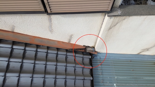 大阪市住吉区での調査。隣家との取り合いにある壁際板金に腐食した木材が落下し、板金が押し潰されて雨漏りの原因になっている様子。