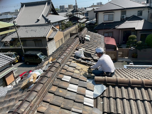 東大阪市の現場で熟練職人が古い土葺き瓦を慎重に解体し下地を清掃している様子