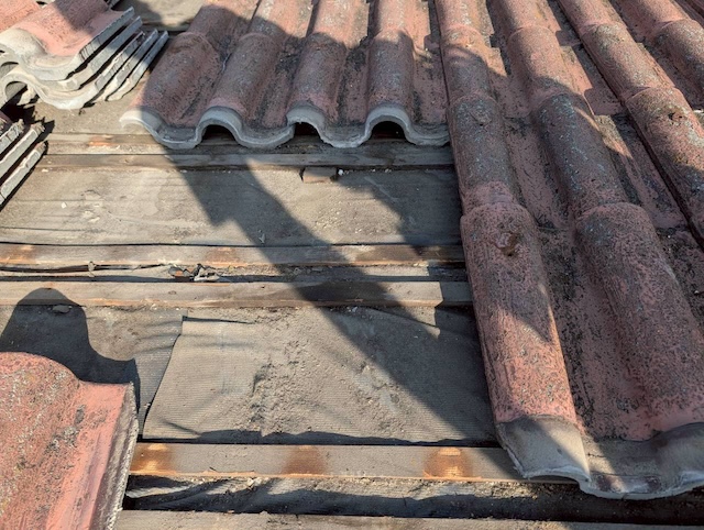 古いセメント瓦を撤去した状態。寿命を迎えて破れ、雨漏りの原因となっていた古い防水シートと下地が露出。