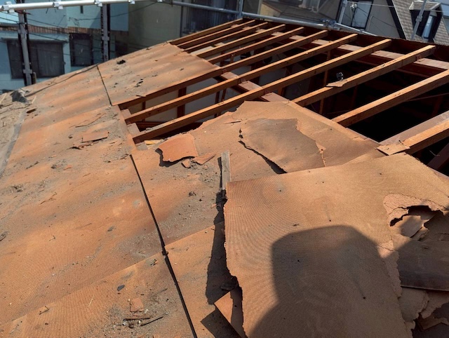 長年の雨漏りで傷んだ古い下地（野地板）を撤去していく様子。