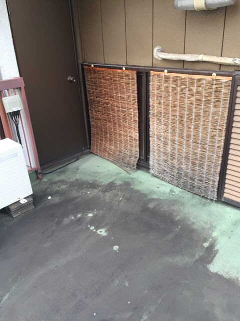すだれがかかったベランダ窓際の床面に広がる黒い変色とコケの劣化
