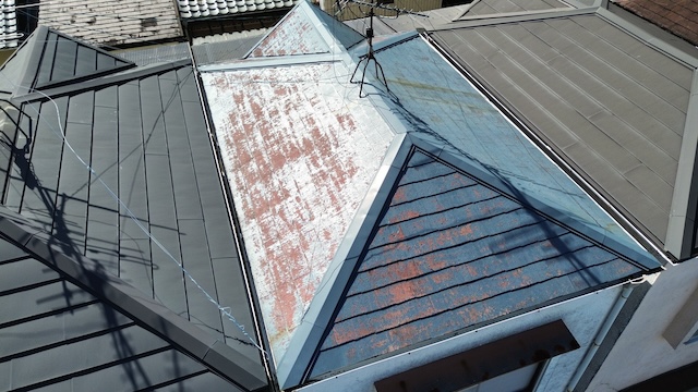 大阪市東成区でのドローン屋根調査。スレート屋根の塗膜が剥がれ、赤茶色の素地が広範囲に露出している様子。