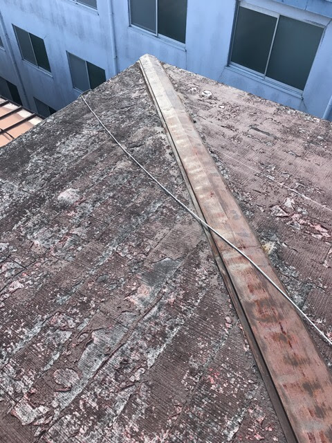 屋根材の表面が層状に剥がれ棟板金にも錆が広がったスレート屋根