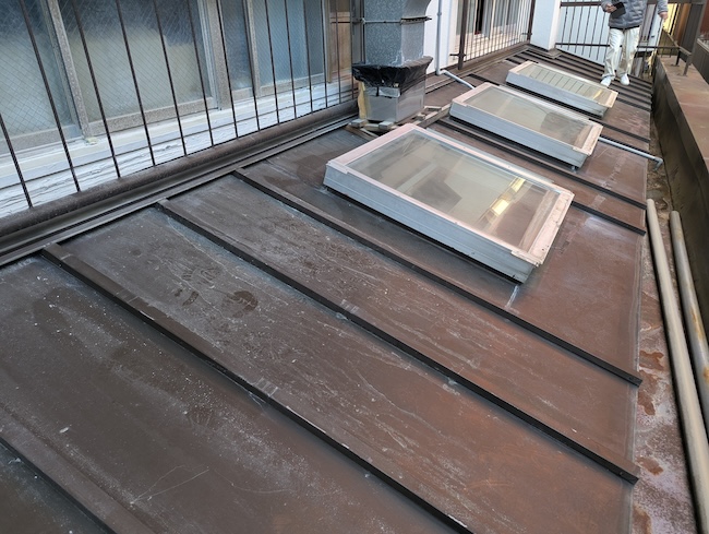 大阪市天王寺区の屋根リフォーム施工前。全体的に色褪せと錆が進行し、雨水が滞留しやすい状態の金属屋根。