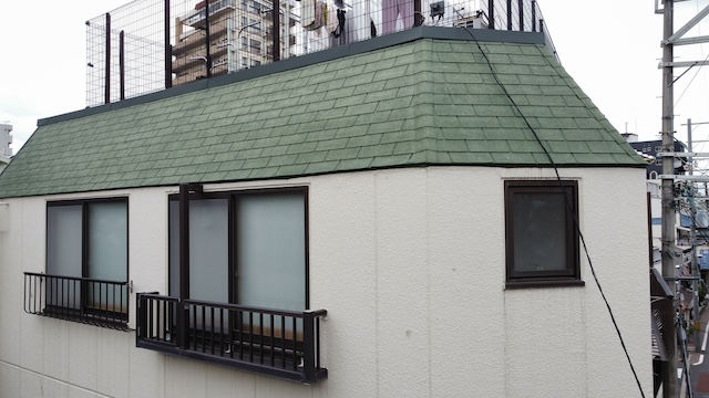 大阪市旭区のマンション施工前。特徴的な急勾配のマンサード屋根に緑色のアスファルトシングルが施工されている