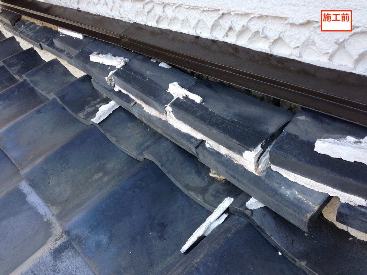 八尾市福万寺での雨漏り修理前。ボロボロになり白い土（漆喰）が剥がれ落ちた壁際の熨斗瓦