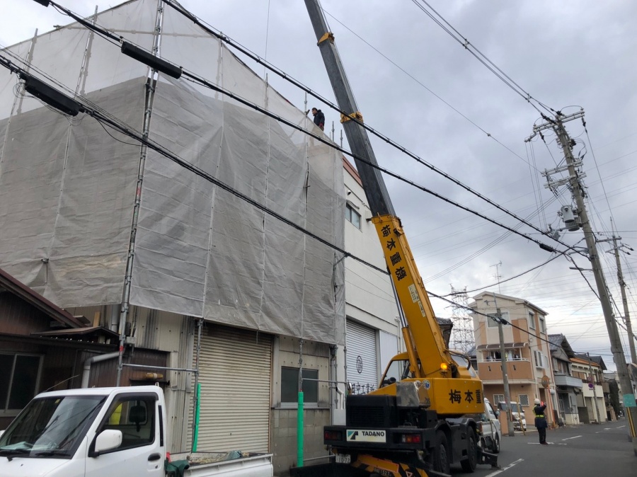 大型クレーンを使用し安全かつ迅速に最新の屋根材リファインルーフを荷揚げする現場風景